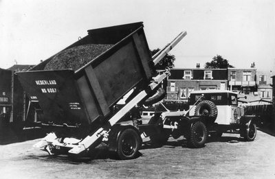 169761 Afbeelding van een vrachtauto van de A.T.O. tijdens het overzetten van een laadkist van de N.S. met steenkolen.